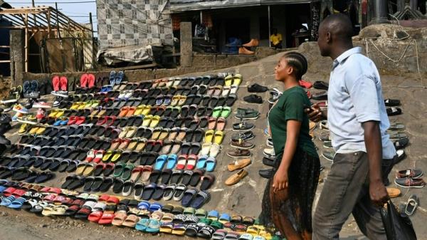 Pedestrians walk past a street vendor's shoe display near Buea in Cameroon. The city has been at the centre of one of Africa's bloodiest co<em></em>nflicts since 2016. Photo: Issouf Sanogo/AFP via Getty Images