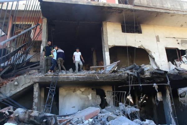 People stand on the landing of a structure that has obvious bomb damage.