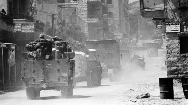 Israeli soldiers in armoured vehicles travel past houses as they pass through a village in the Bekaa Valley during the Israeli invasion of Lebanon, named 