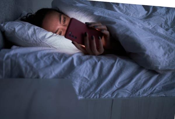 A person laying in bed looking at a phone