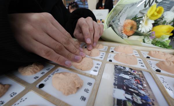 A graduate from the Daegu Gwangmyung School, a school for the visually imparied, goes through the school's 3D printed yearbook on Jan. 8. (Yonhap)
